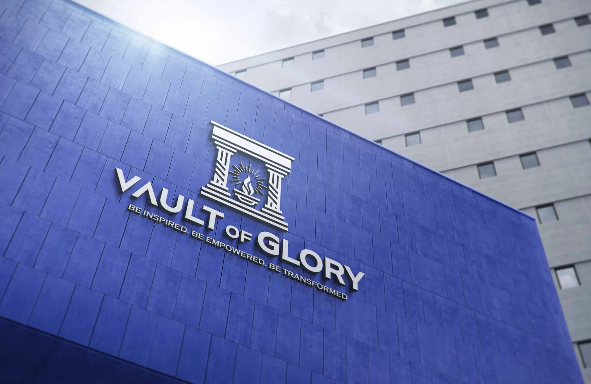The Vault of Glory identity — a temple mark with a lit torch, and the words 'Vault of Glory · Be inspired, be empowered, be transformed' — mounted large on a building facade.